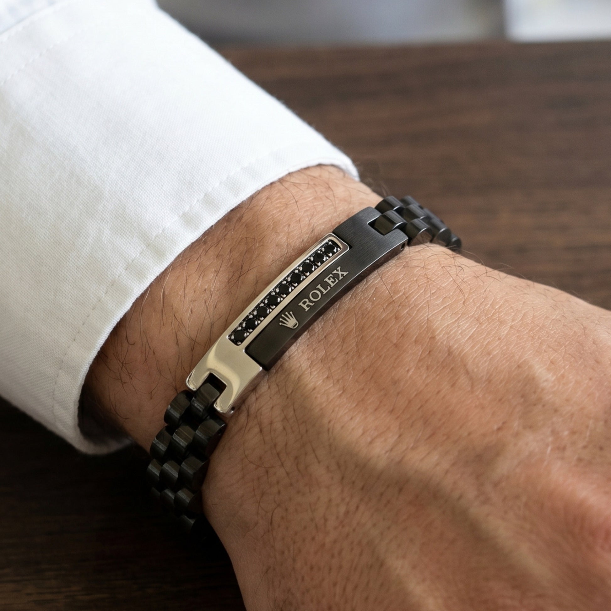 Silver and black stainless steel B-150 bracelet on a man's wrist, featuring a sleek design and clasp detail.