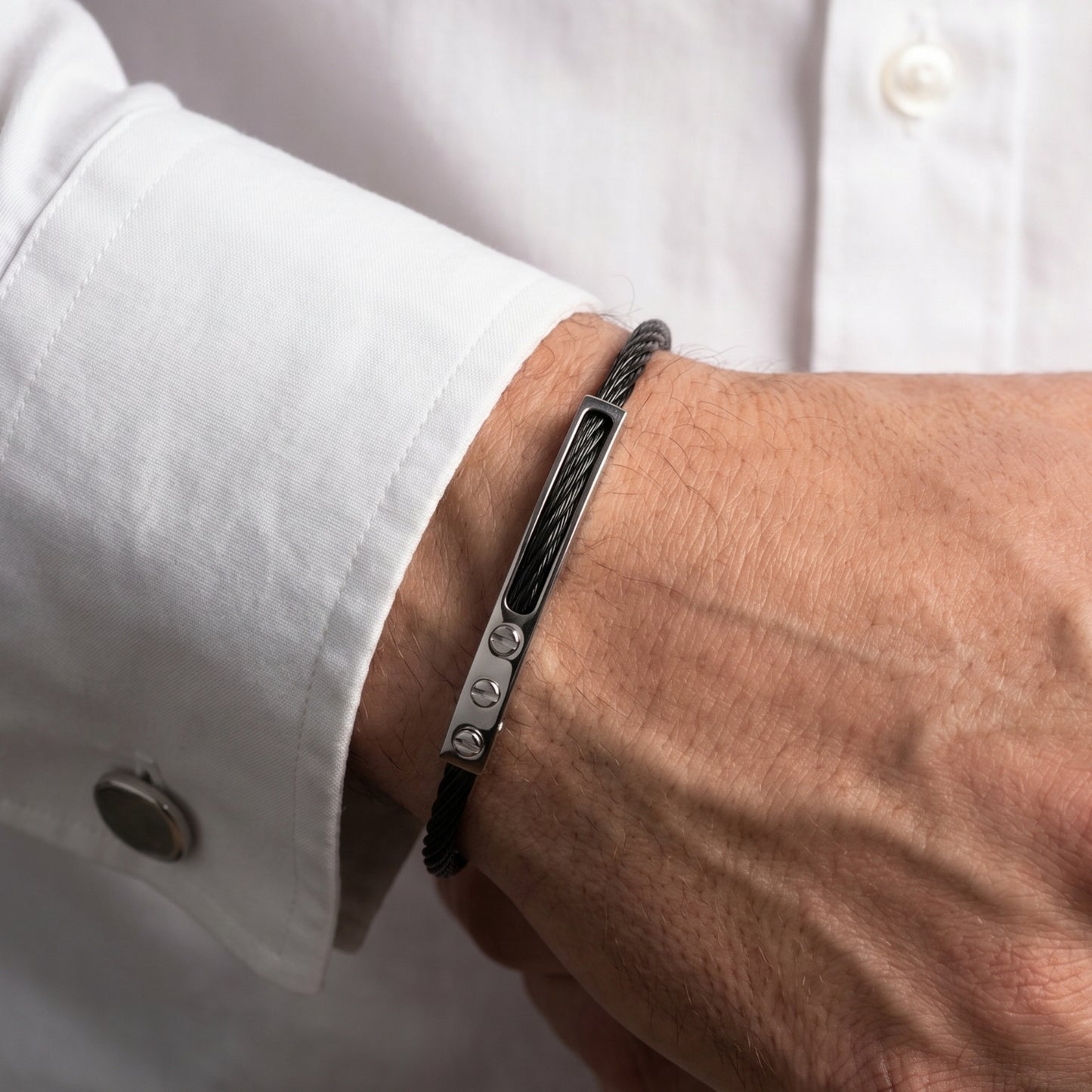 Black bracelet on a wrist with a white shirt background