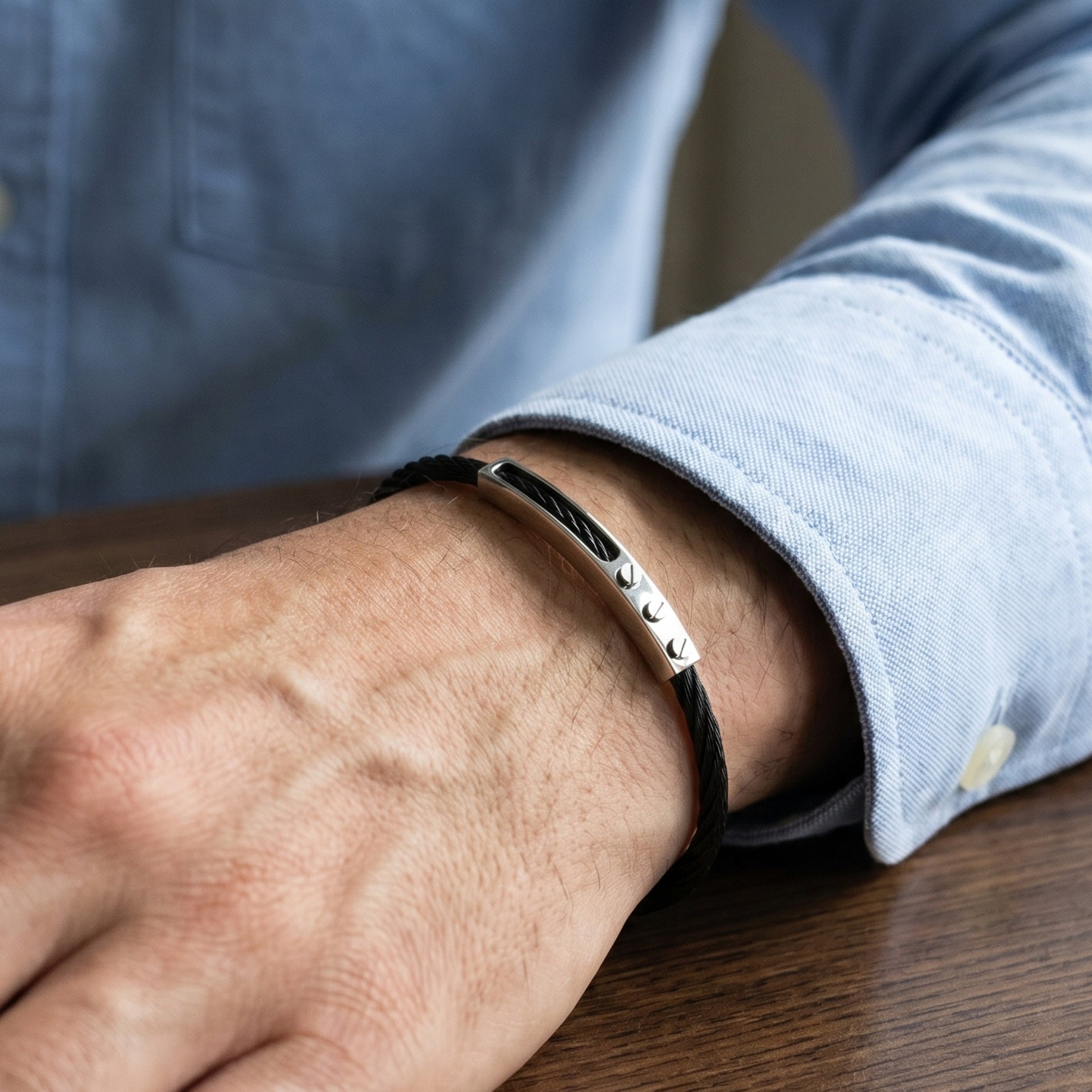 Close-up of a person's wrist wearing a silver bracelet with a blurred background