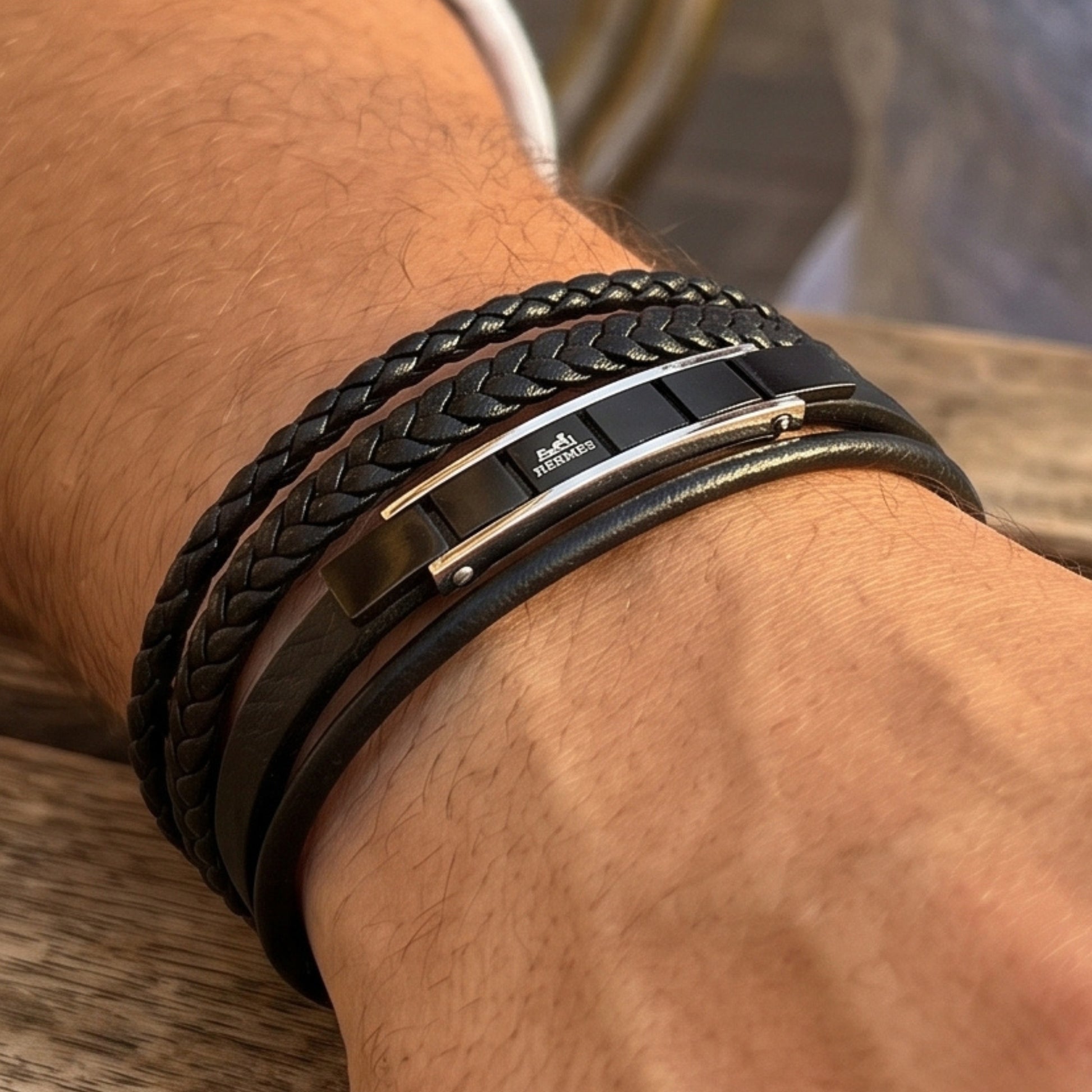 Black leather bracelet on wrist with braided strap and silver metal center clasp