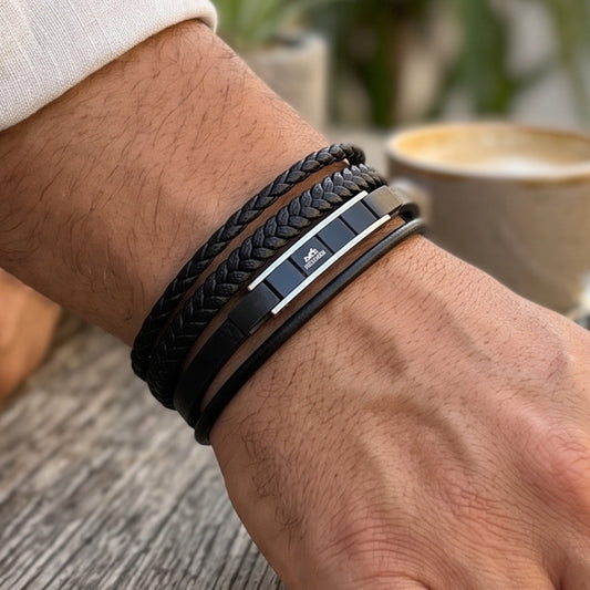 Black leather men's bracelet on wrist with stacked bands and silver-toned metal plates