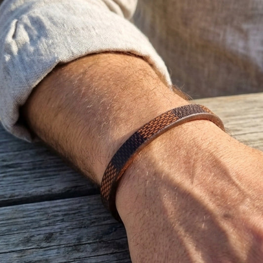 Leather bracelet on wrist: brown strap with navy-orange woven band and black buckle