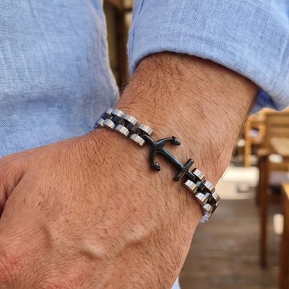 Anchor charm bracelet featuring black anchor and two-tone stainless link band, worn on arm.