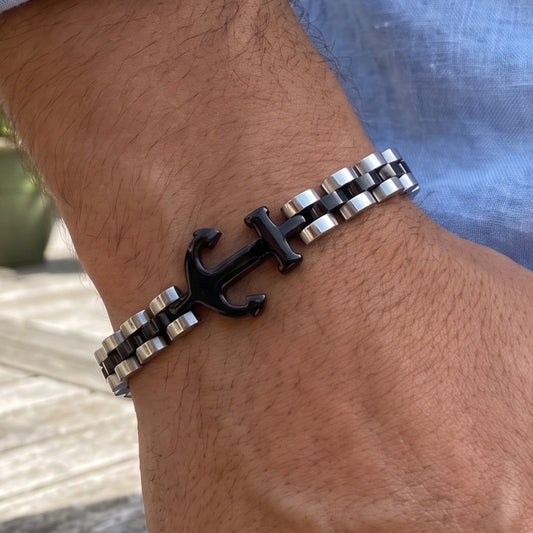 Men's anchor bracelet on wrist, black anchor charm with silver and dark metal links.