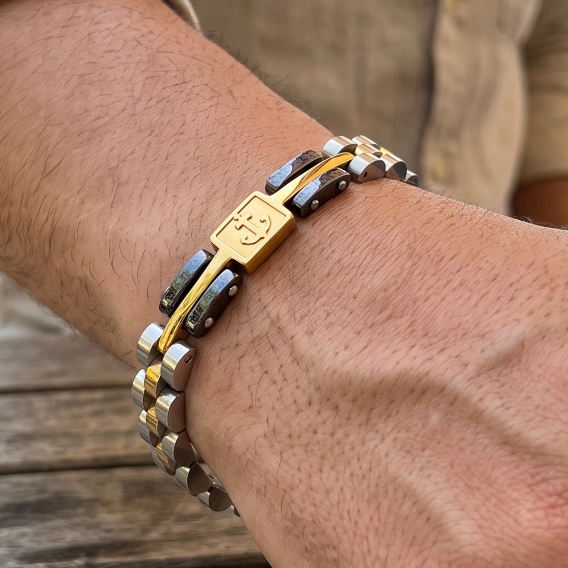 Anchor emblem clasp on tri-tone bracelet, silver and gold links with black inlays