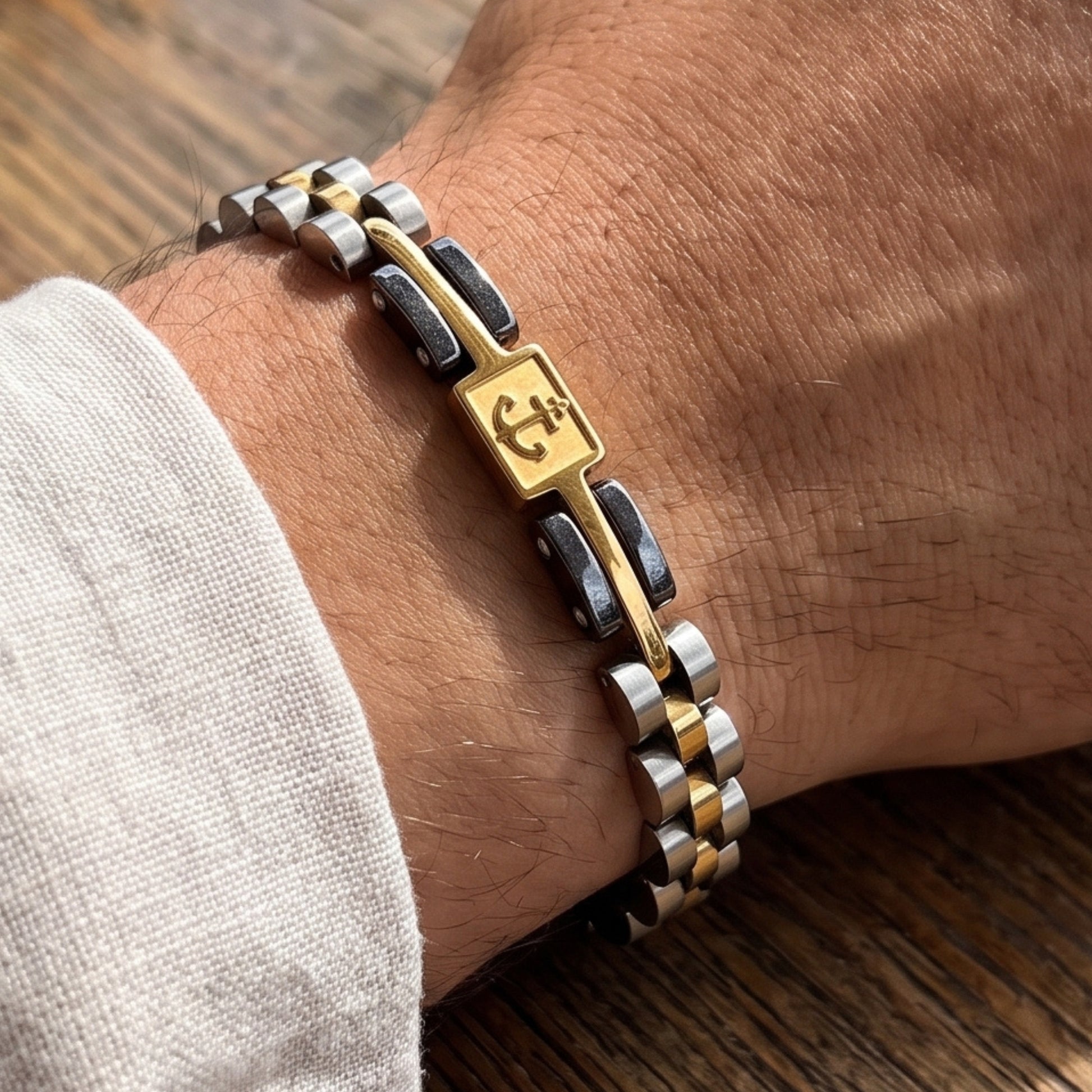 Tri-tone stainless anchor bracelet on wrist, silver-gold-black links with emblem panel