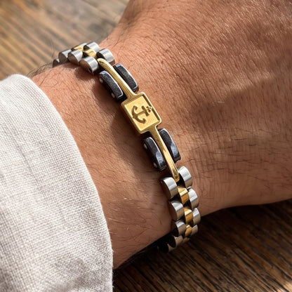 Tri-tone stainless anchor bracelet on wrist, silver-gold-black links with emblem panel