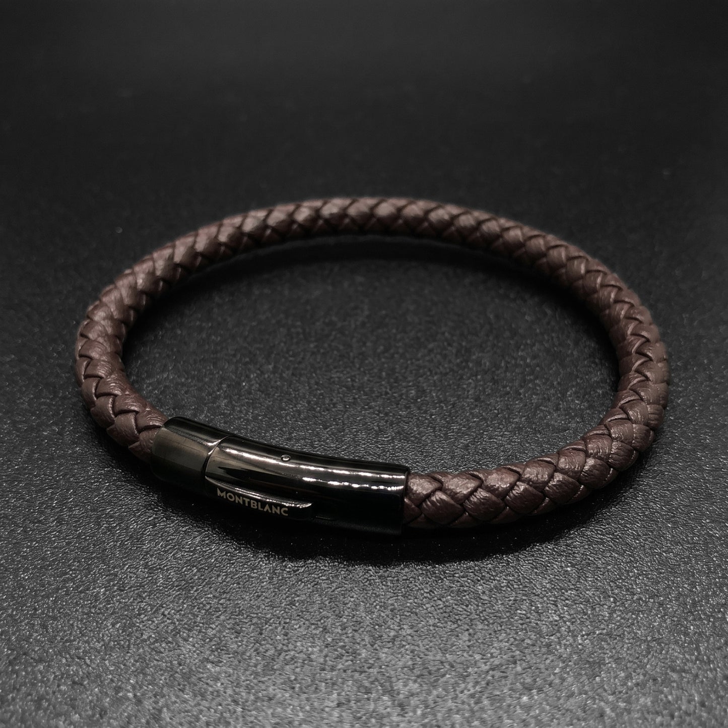 Brown braided leather bracelet with side view of rectangular clasp and logo