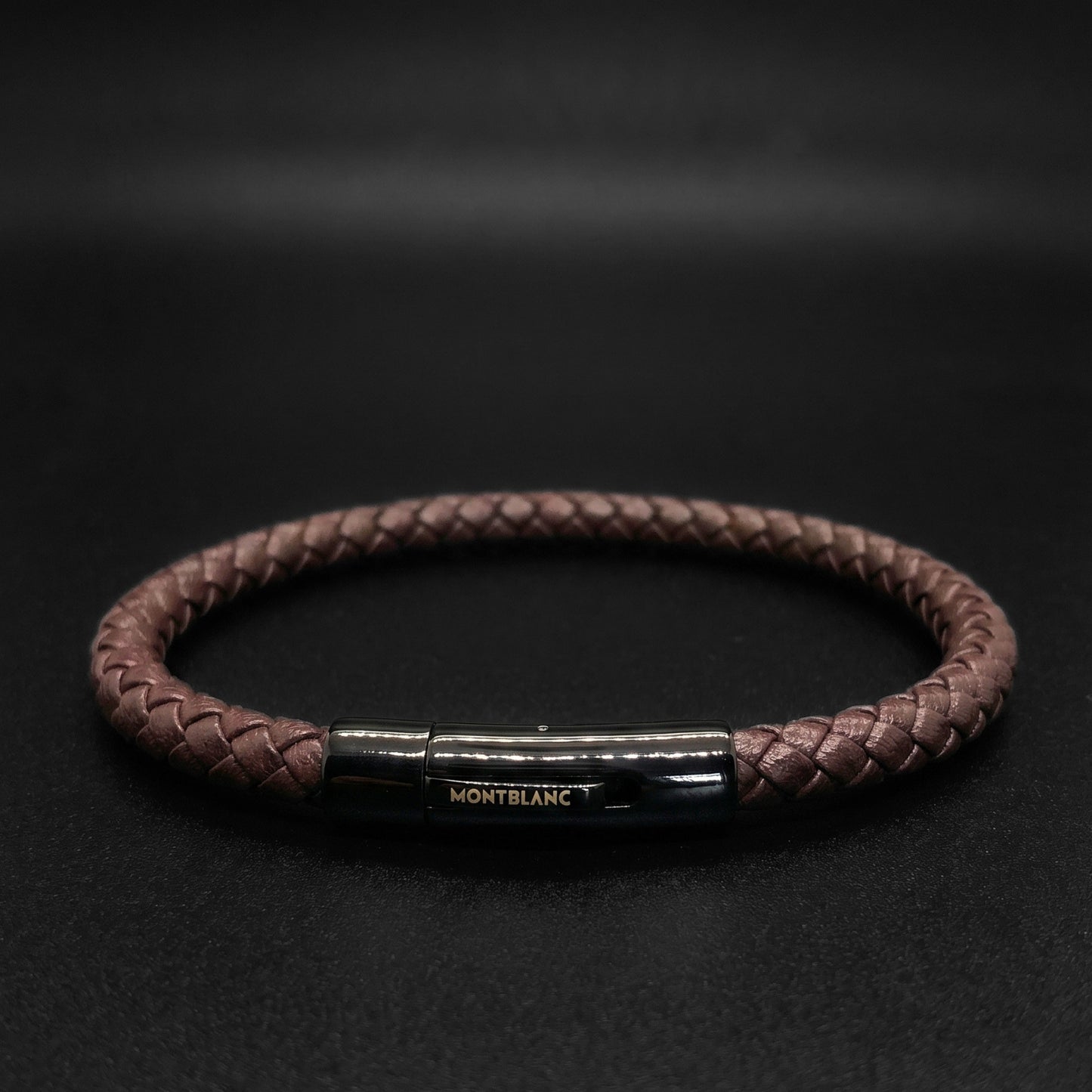 Brown braided leather bracelet with rectangular metal clasp and engraved logo