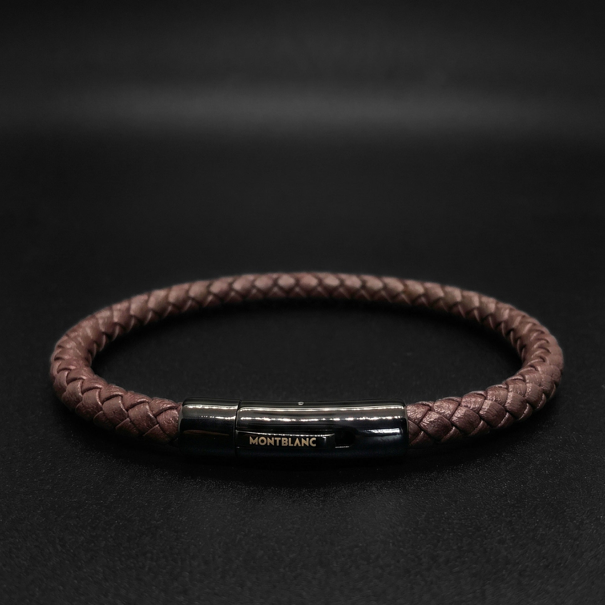 Brown braided leather bracelet with rectangular metal clasp and engraved logo