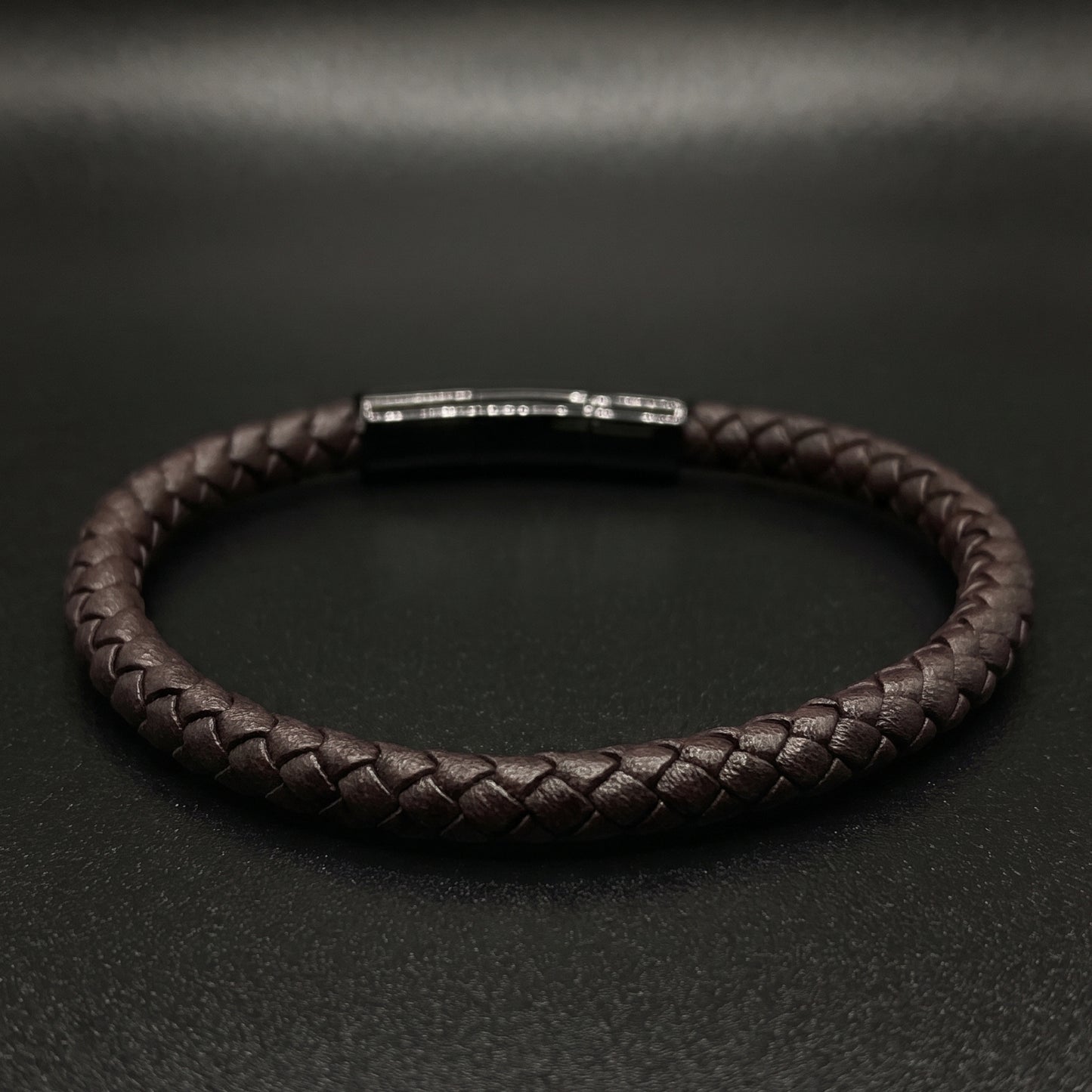 Braided leather bracelet showing rectangular metal clasp and shiny top detail