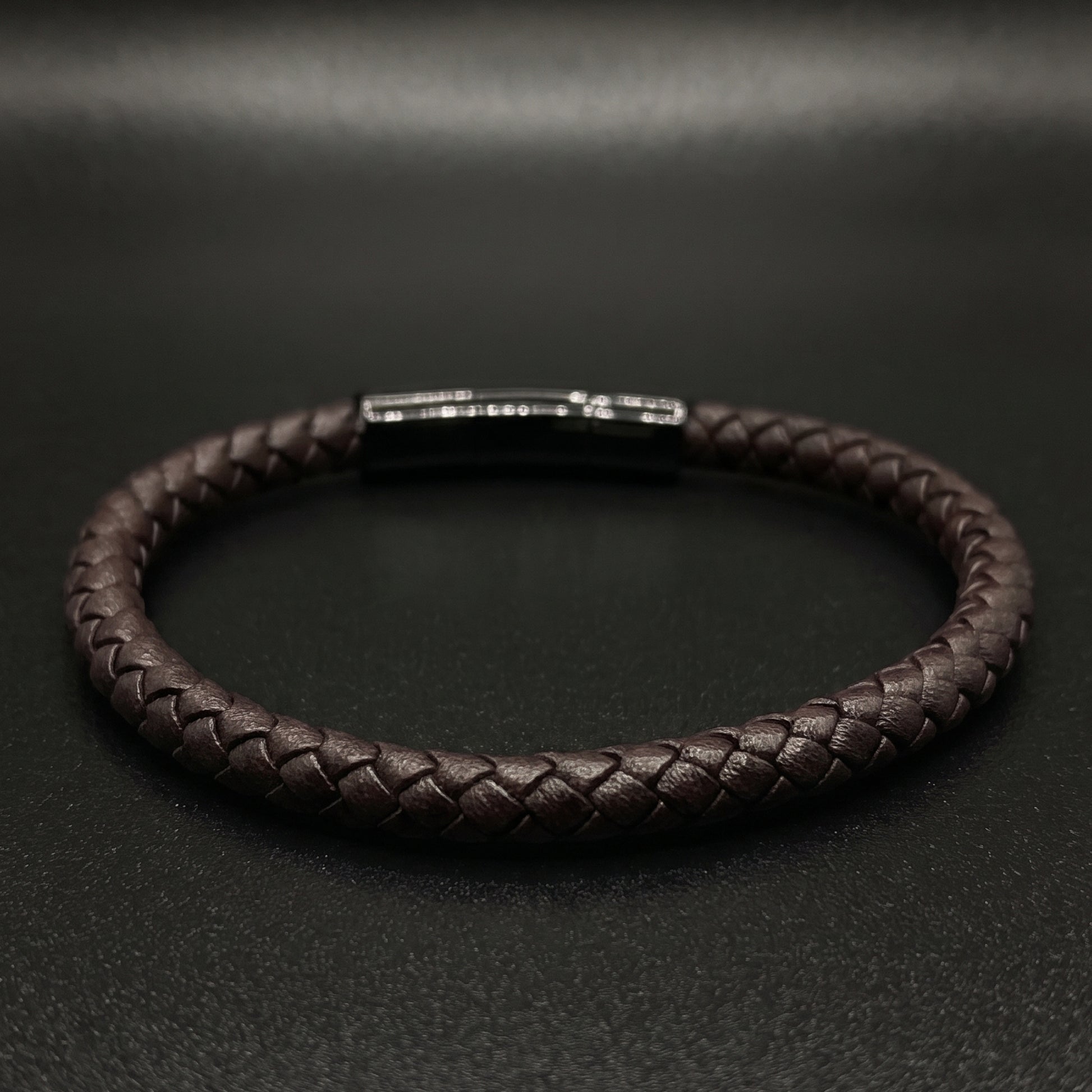 Braided leather bracelet showing rectangular metal clasp and shiny top detail