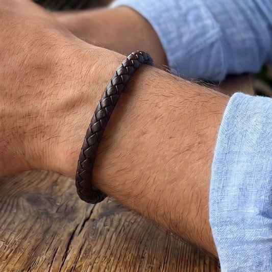 Leather bracelet on wrist, braided dark brown band with metal clasp detail