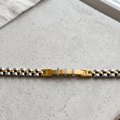 Two-tone stainless steel bracelet close-up, gold center bar with silver links