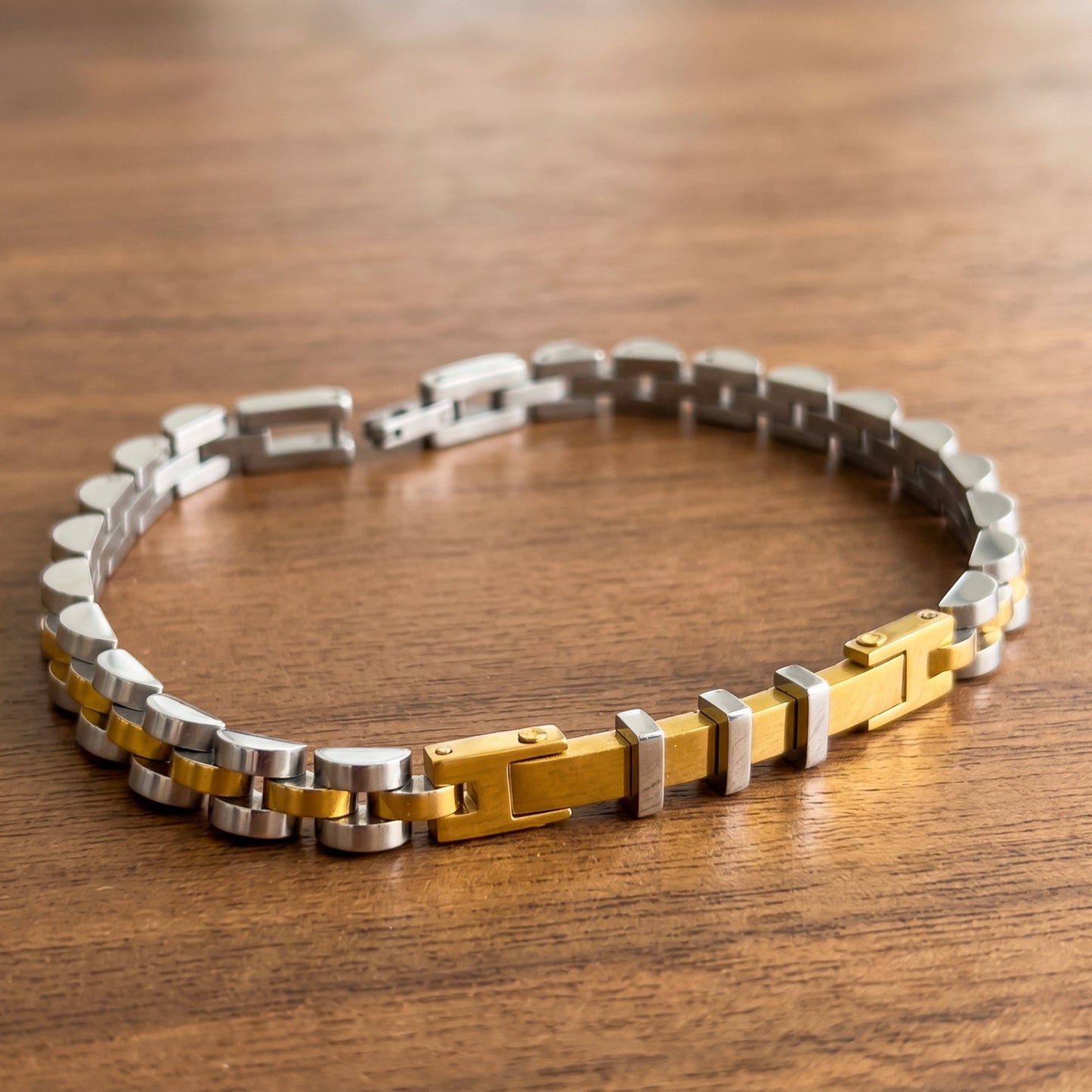 Two-tone stainless steel bracelet laid flat, alternating silver and gold link design
