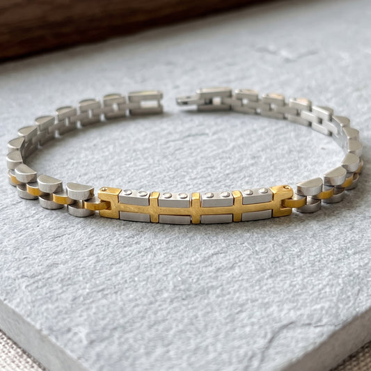 Two-tone silver and gold link bracelet with gold center cross on display base