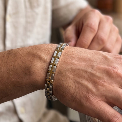 Two-tone silver and gold stainless steel bracelet on wrist with link and cross detail