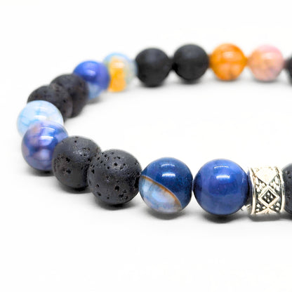 Men's bracelet detail with black lava beads, blue agate beads, and silver geometric charm