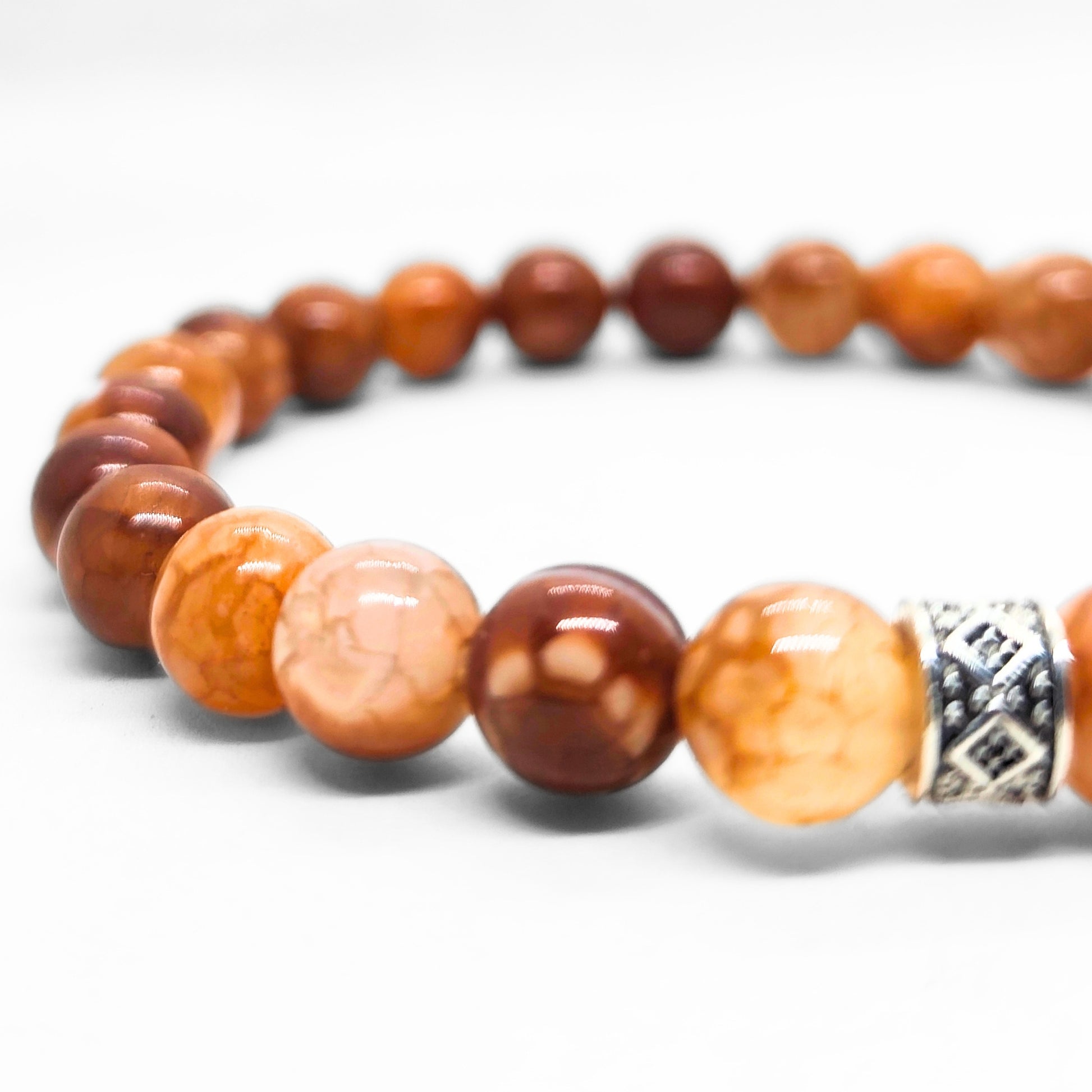Close-up of men's brown stone bead bracelet with silver patterned spacer detail