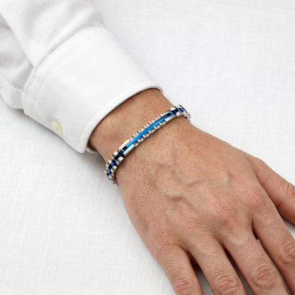 Two-tone bracelet with blue and silver links on a hand in a white shirt