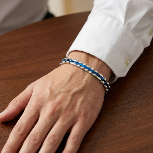 Two-tone stainless steel bracelet with blue stripe links on wrist resting on table