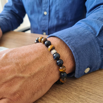 Mens bracelet on wrist: dark navy and amber tiger eye beads with silver geometric center charm