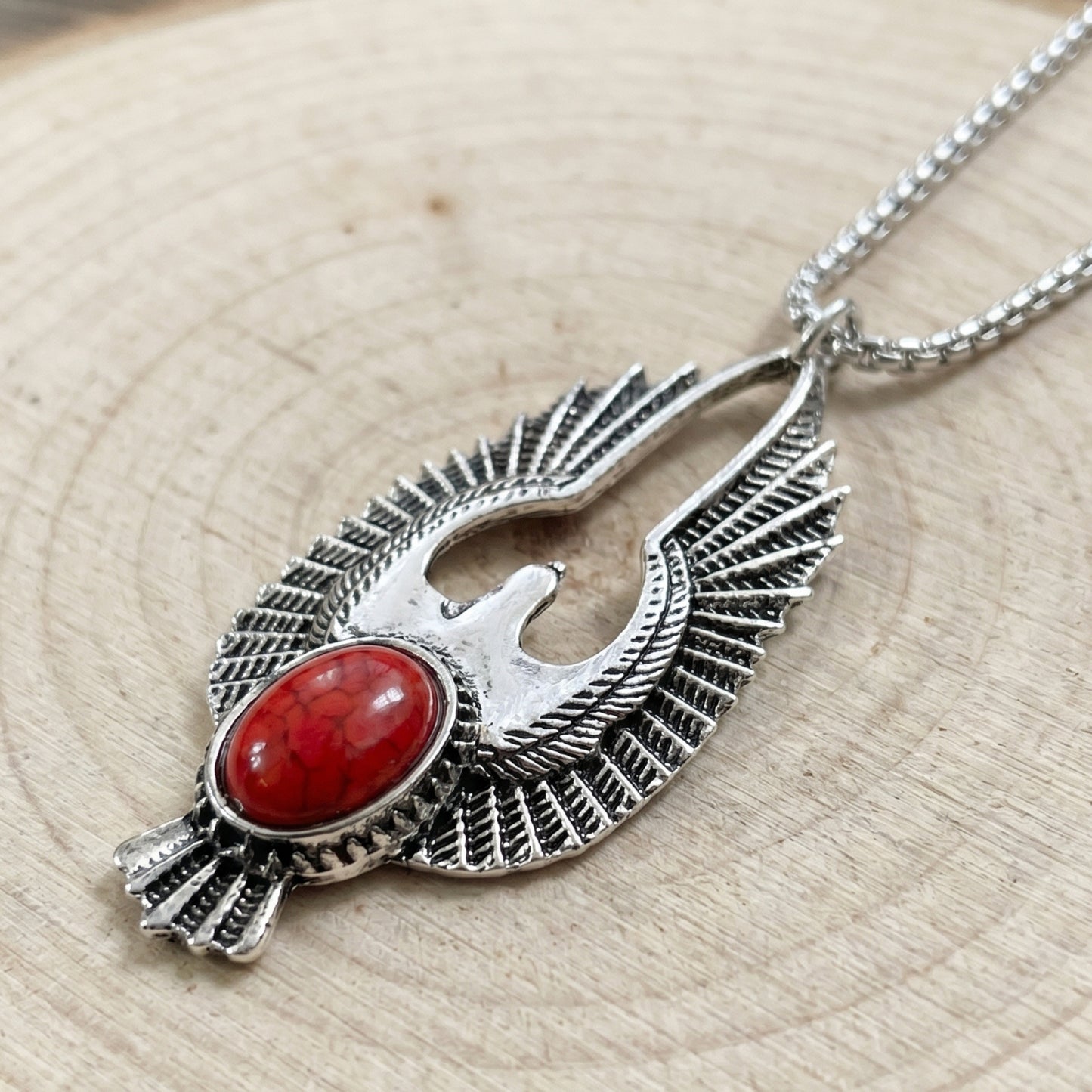 Silver-tone eagle pendant with red oval stone, textured wings, on metal chain