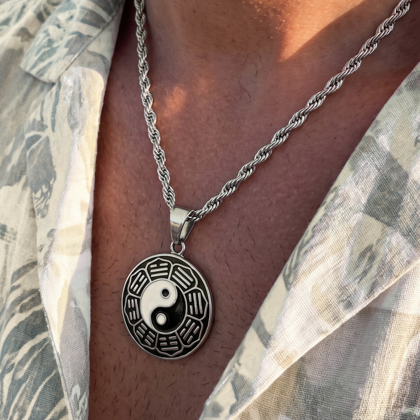 Silver yin-yang pendant necklace with circular dark-and-silver pendant on steel chain