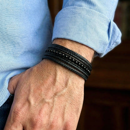 Premium Black Leather Sleek Men's Bracelet - B-125 from Overpowered Accessories, worn on a wrist with a blue shirt.