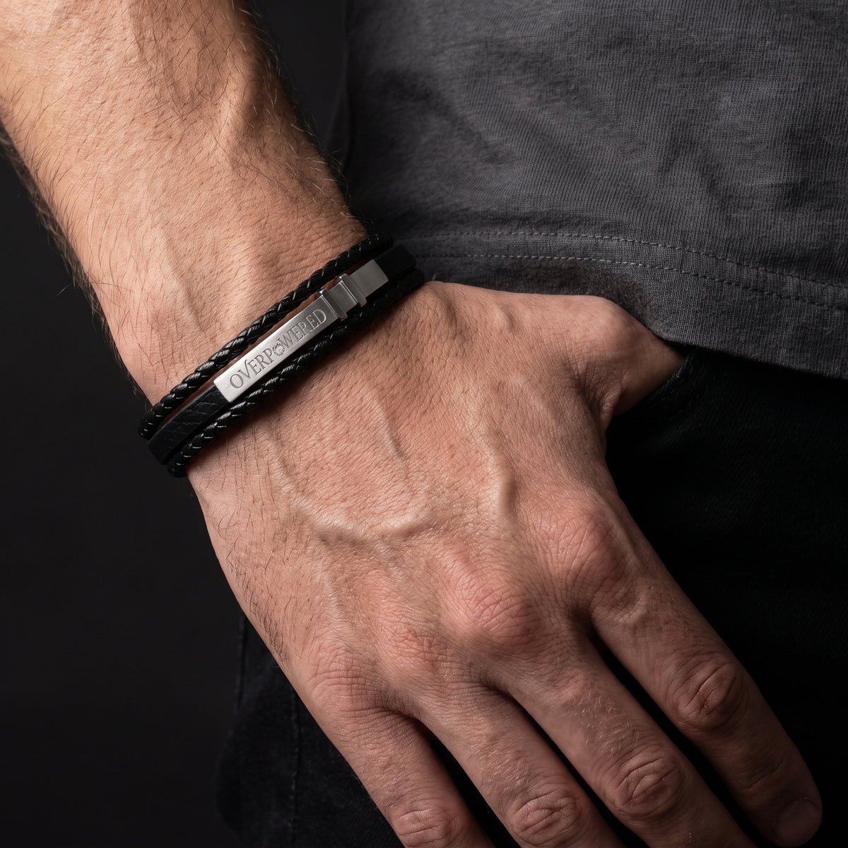 Black leather bracelet with silver clasp and engraved logo on wrist