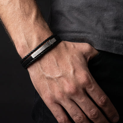 Black leather bracelet with silver clasp and engraved logo on wrist