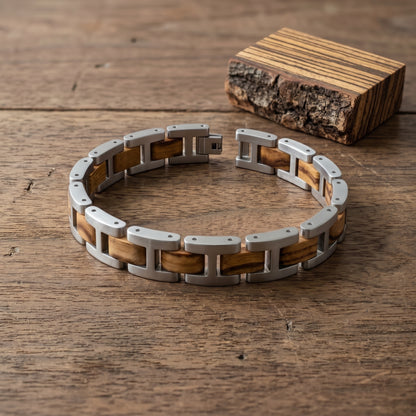 Men's zebrawood and stainless steel link bracelet on wood table, beside a wood block, Overpowered Accessories