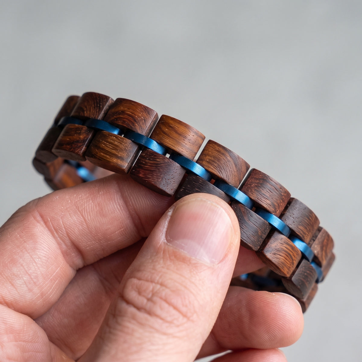 Close-up of rosewood wood block bracelet with blue inlay strips and metal clasp, Overpowered Accessories