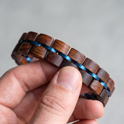Close-up of rosewood wood block bracelet with blue inlay strips and metal clasp, Overpowered Accessories