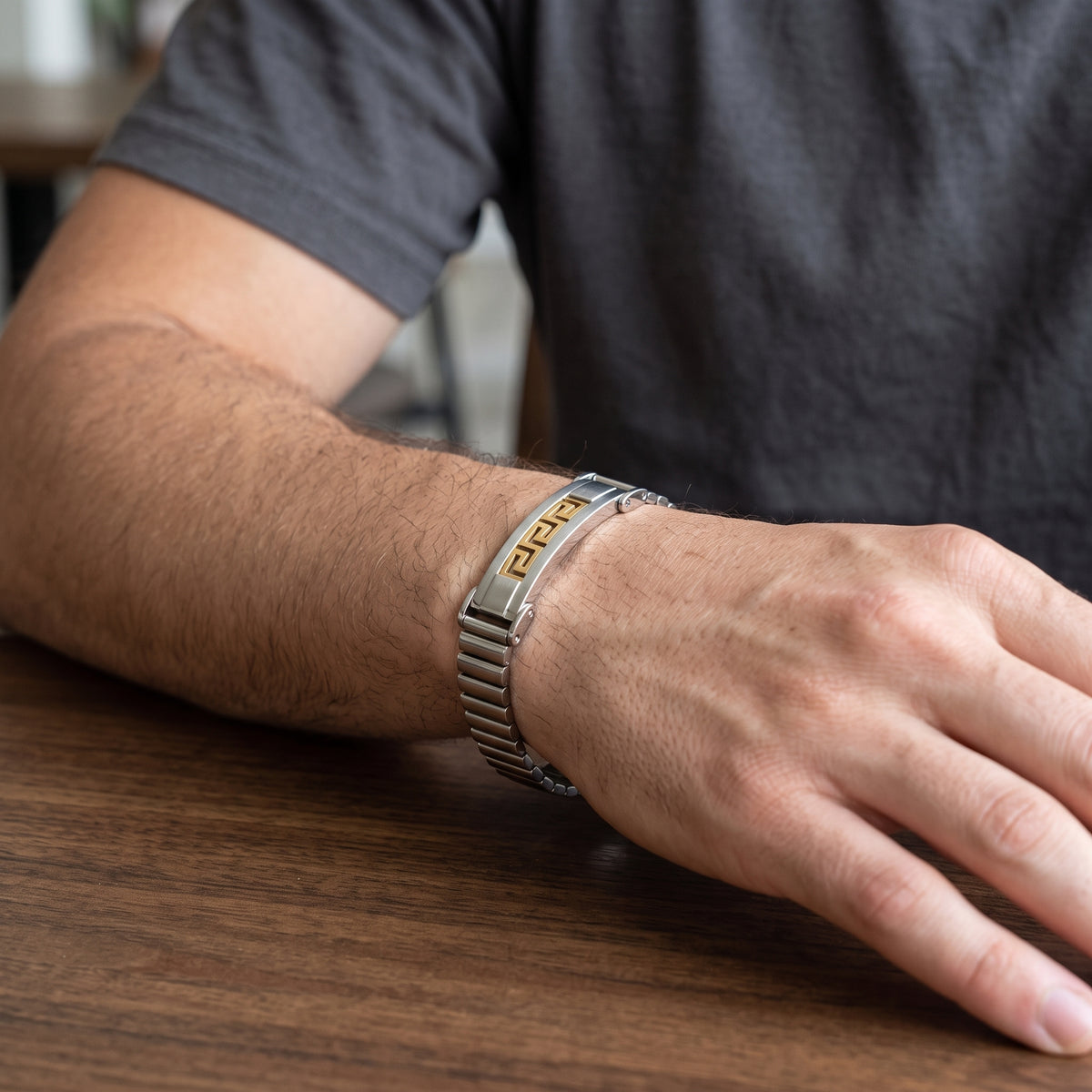 Men's silver stainless bracelet with gold Greek key center and watch clasp on wrist