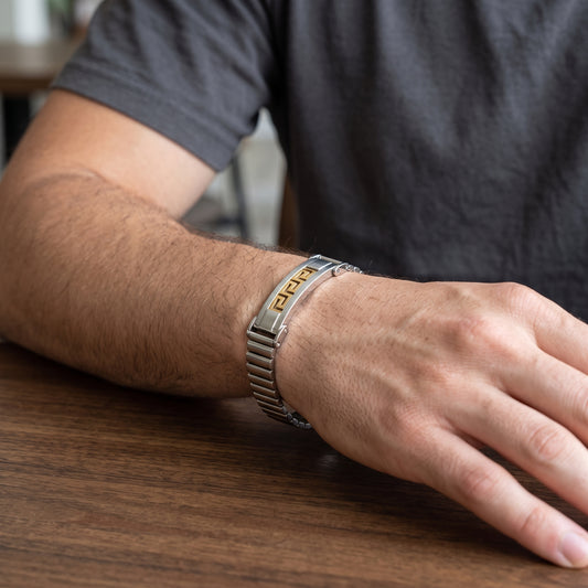 Men's silver stainless bracelet with gold Greek key center and watch clasp on wrist