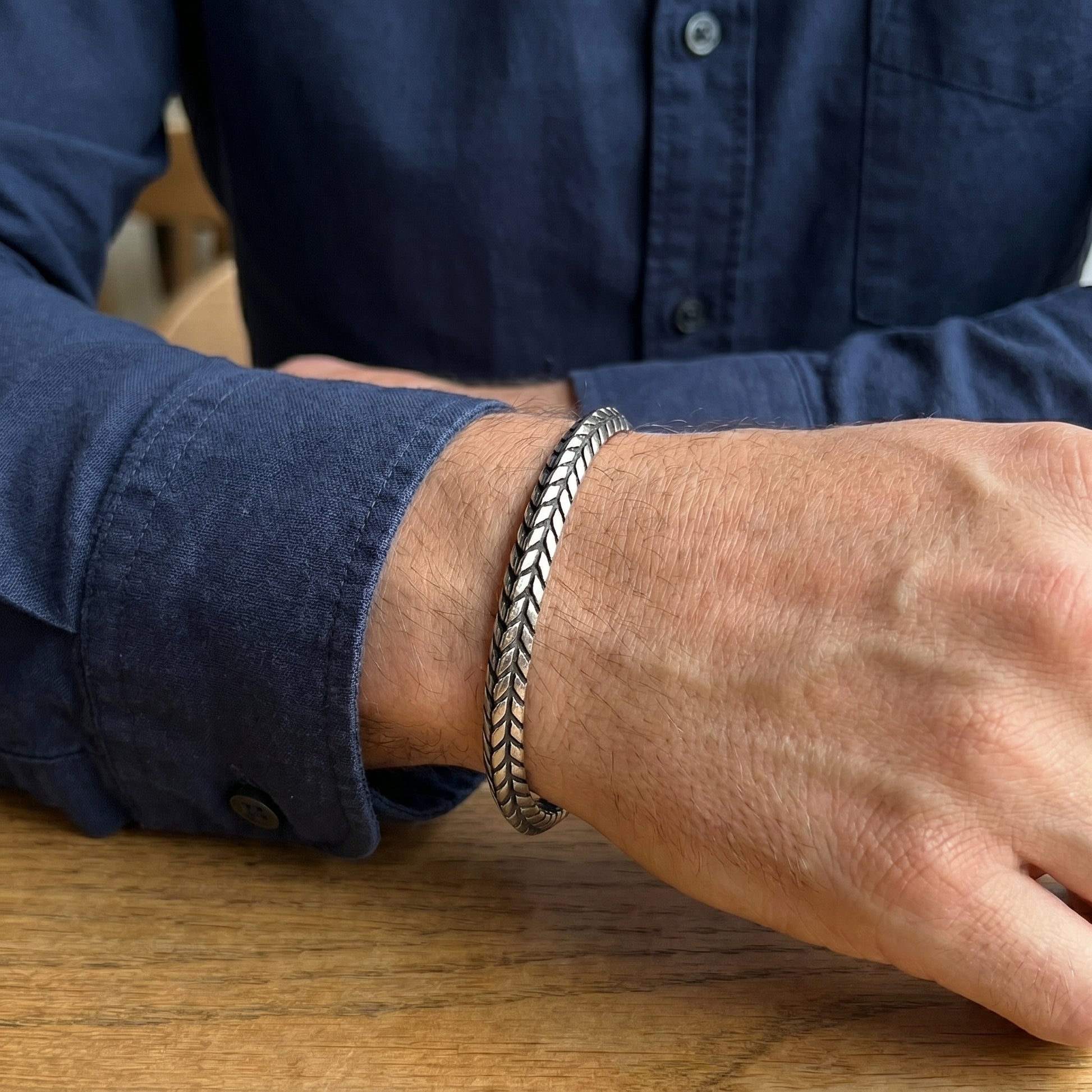Silver stainless steel braided cuff bracelet on wrist, side view while resting.