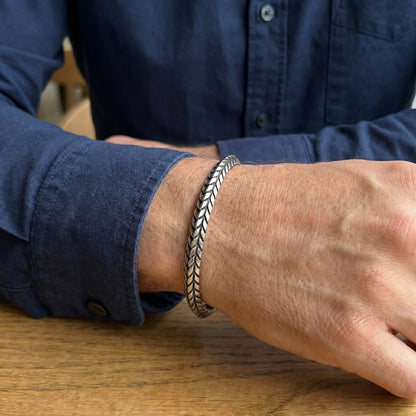 Silver stainless steel braided cuff bracelet on wrist, side view while resting.