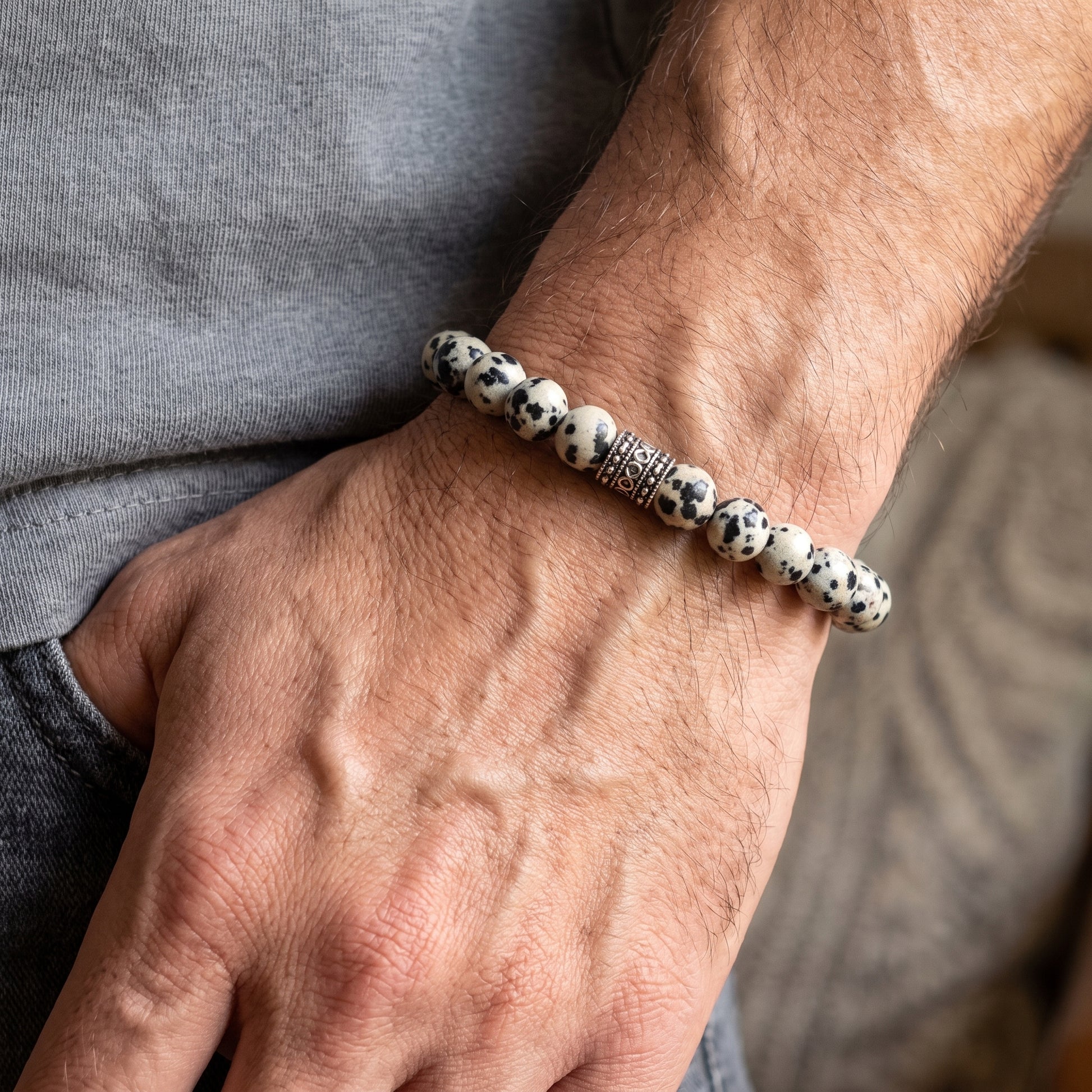Dalmatian jasper bead bracelet on hand, speckled stones and engraved silver-tone center bead