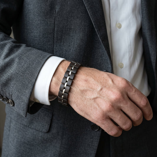 Men's dark ebony wood bracelet with silver segmented metal links, wrist view