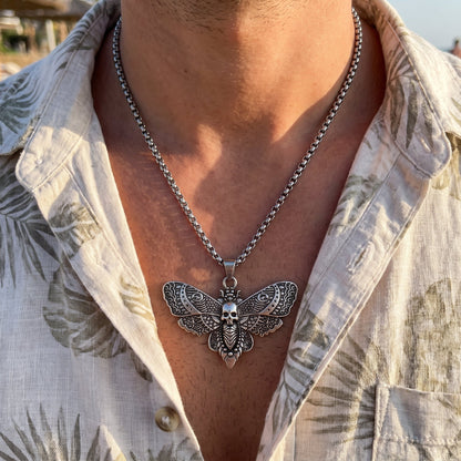 Silver-tone butterfly skull pendant necklace worn with long chain at collar