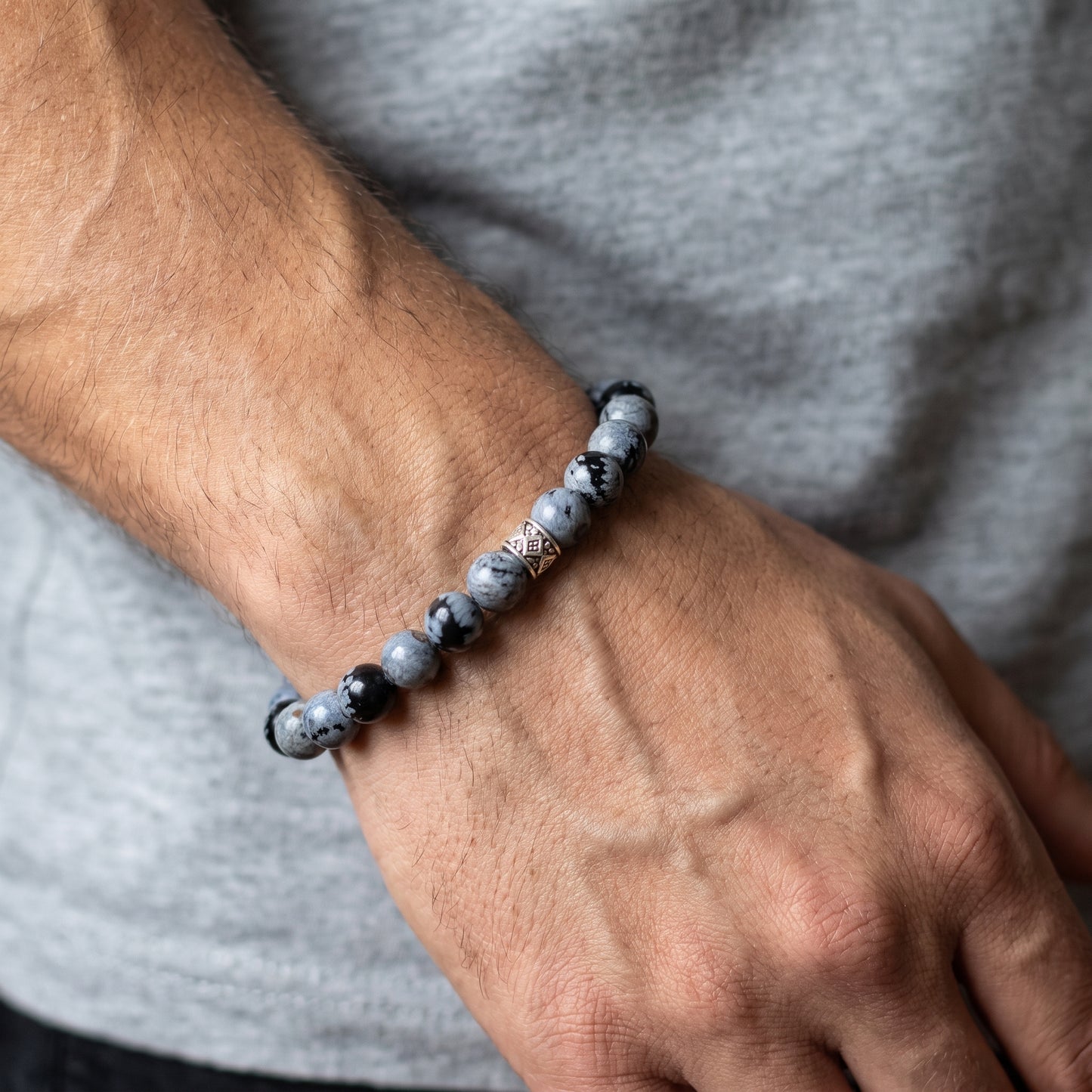 Men’s obsidian bead bracelet on wrist featuring round gray-and-black speckled beads