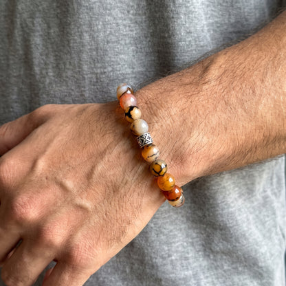 Natural agate bracelet on wrist with orange, tan, black, and white beads and silver geometric link