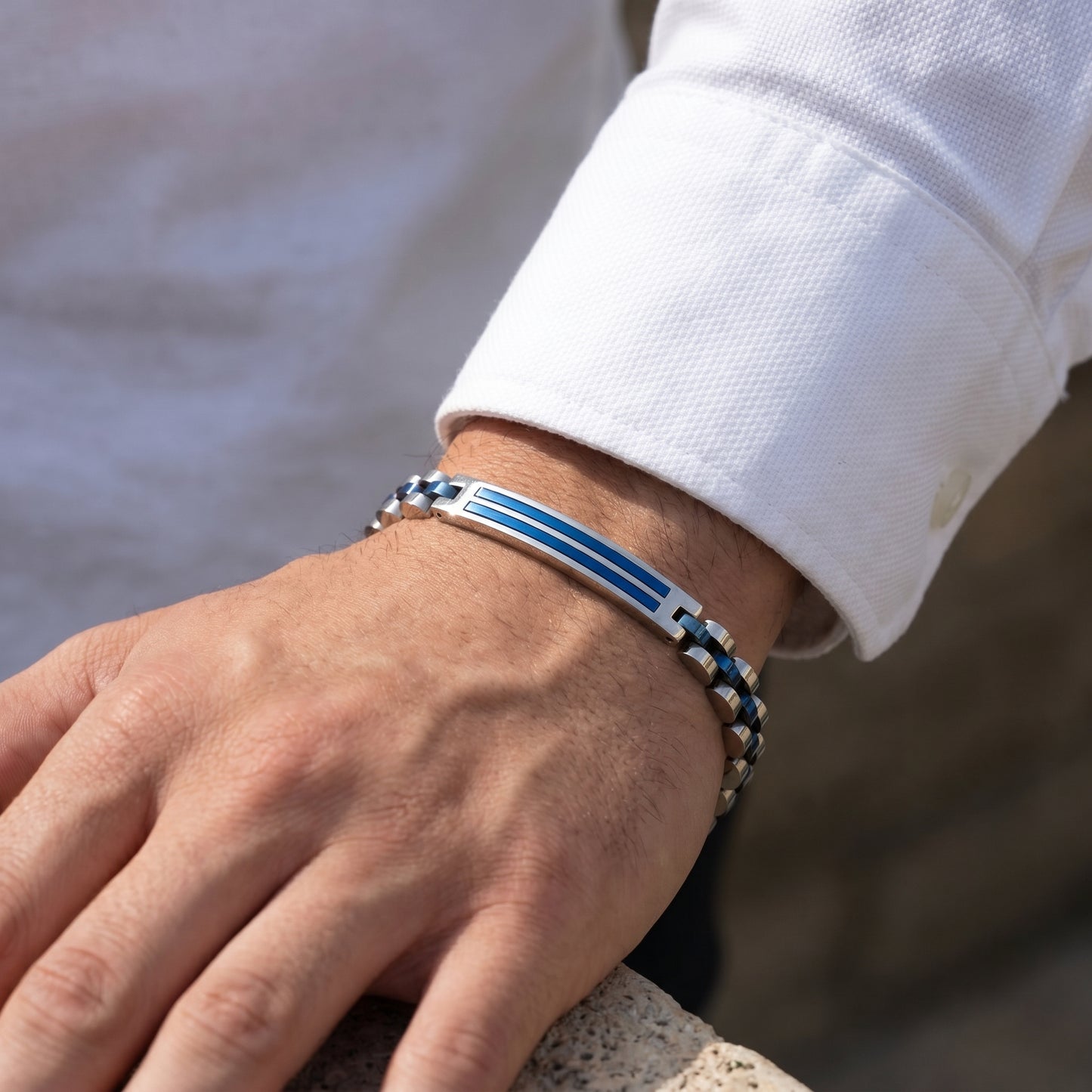 Men's stainless steel bracelet with blue inlay on wrist next to white shirt cuff