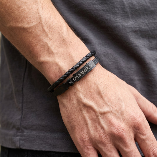 Black braided leather bracelet with dark plate clasp reading OVERPOWERED.