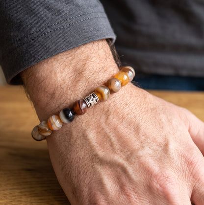 Beaded agate bracelet on hand with silver spacer and brown, black, and white beads