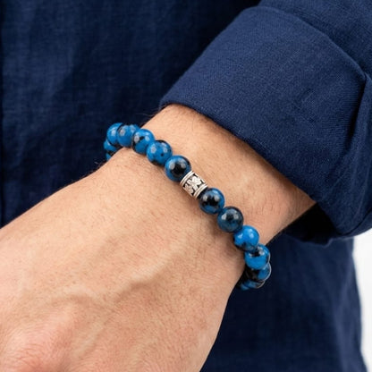 Stone bead bracelet on man's wrist with blue shirt sleeve and silver clasp