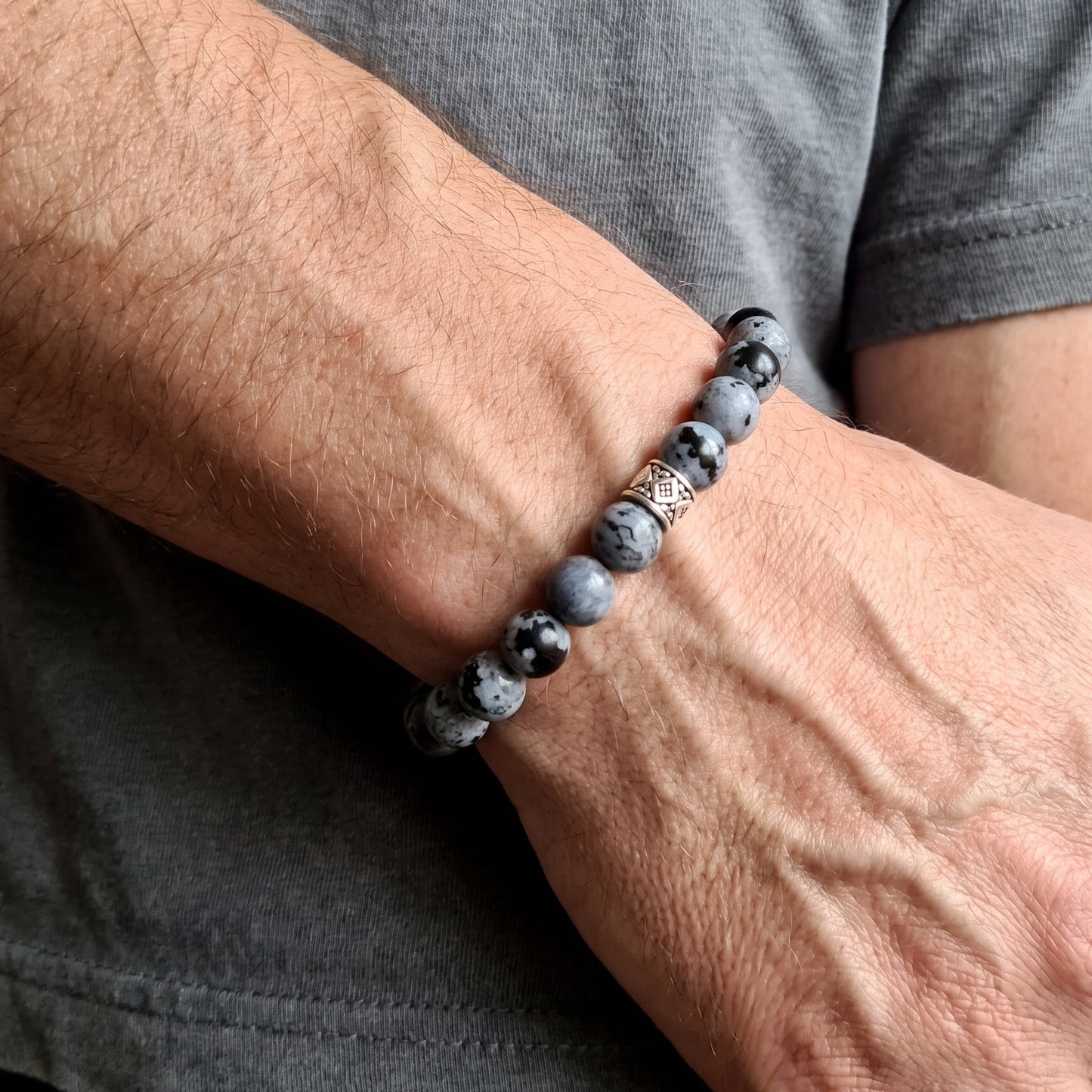 Close-up of obsidian bead bracelet on wrist with silver geometric bead center