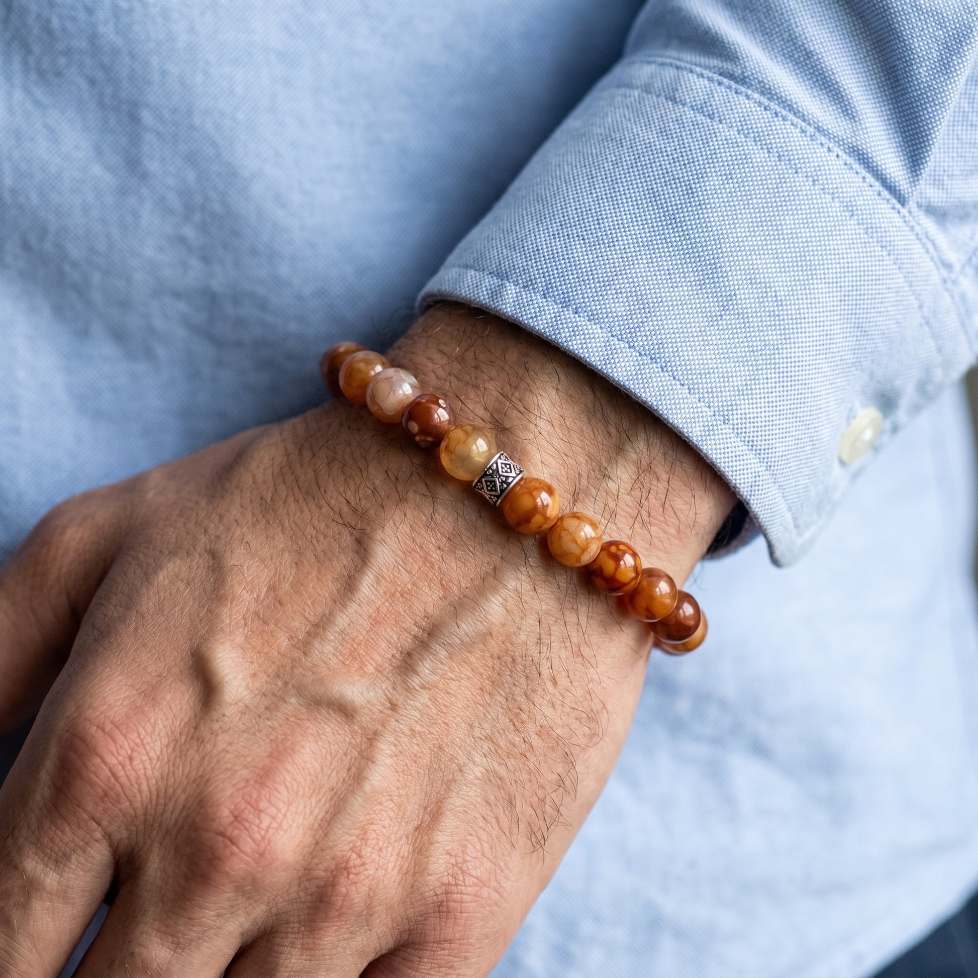 Men's brown gemstone bead bracelet on wrist with silver patterned center spacer
