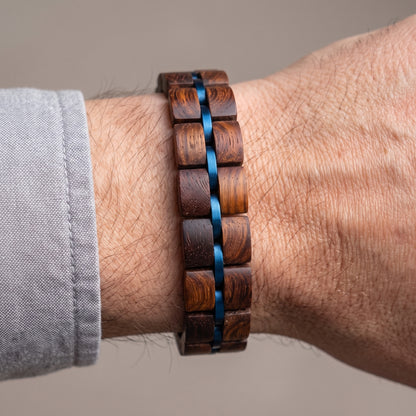 Men's rosewood wood block bracelet with blue ribbon-style inlays, worn on wrist, Overpowered Accessories